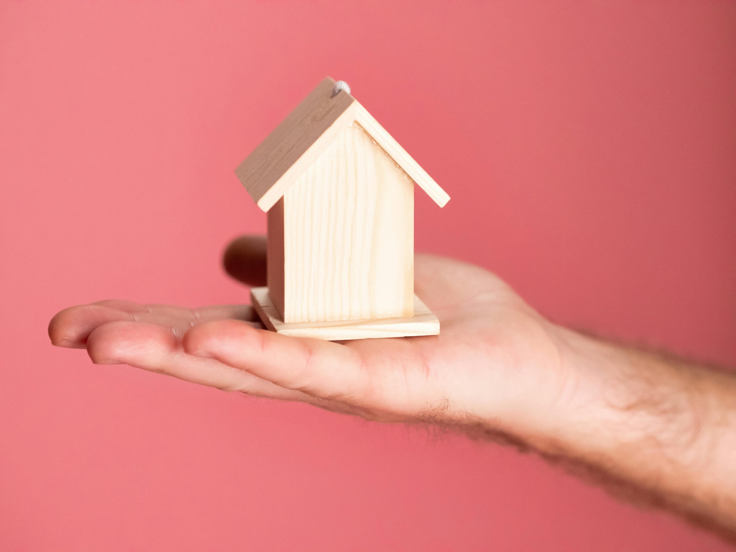 man holding a miniature wooden house